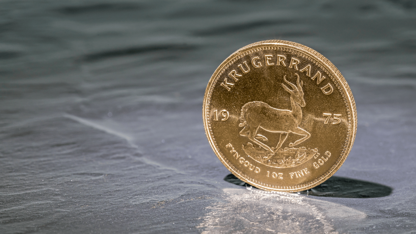 una moneta Krugerrand in oro in verticale su una superficie riflettente